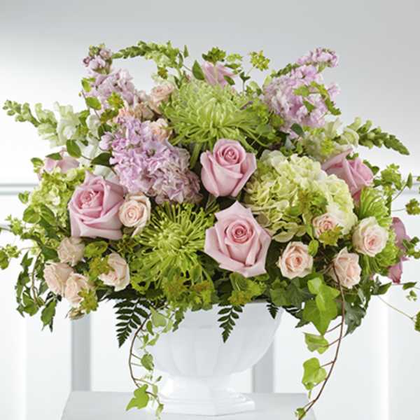 Large pastel arrangement with pink roses, green mums, and hydrangeas in a white pedestal bowl
