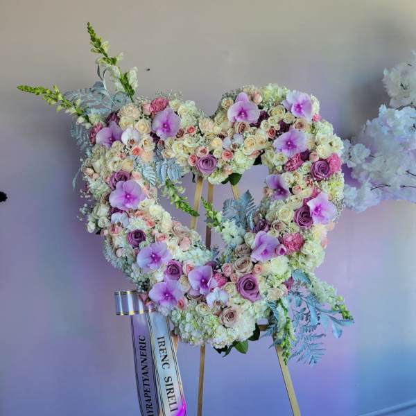 Large heart-shaped standing wreath of white and lavender flowers with orchids on a wooden easel