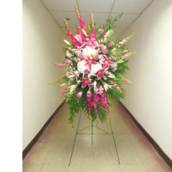 Tall pink and white standing spray with lilies and roses on a metal easel.