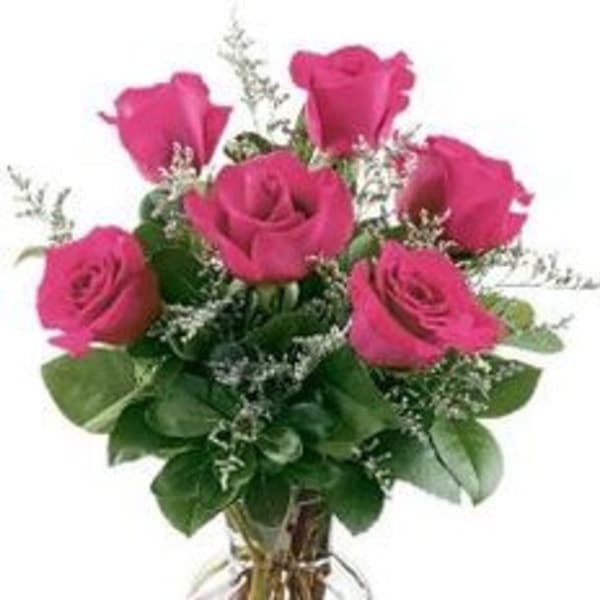 Clear glass vase of hot pink roses with white accent blooms