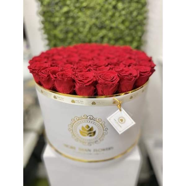 Round white hat box filled with tightly packed red roses