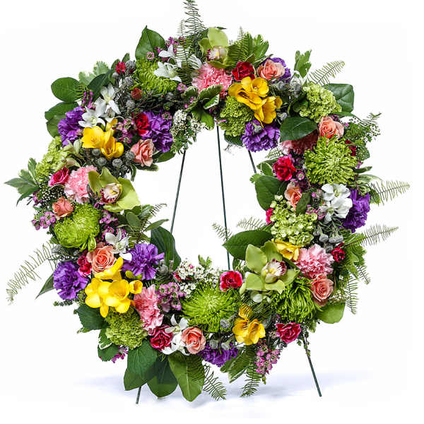 Colorful mixed flower wreath with roses, orchids, mums, and carnations on a metal stand