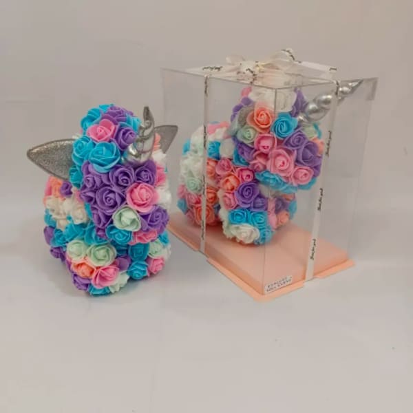 Pastel unicorn-shaped arrangement of artificial roses, one displayed inside a clear gift box.