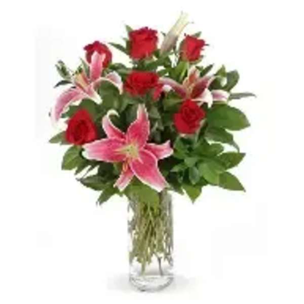 Bouquet of red roses and pink lilies in a clear glass vase