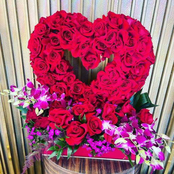 Heart-shaped arrangement of red roses with purple orchids