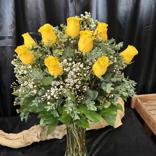 Yellow roses arranged in a clear glass vase with small white filler flowers