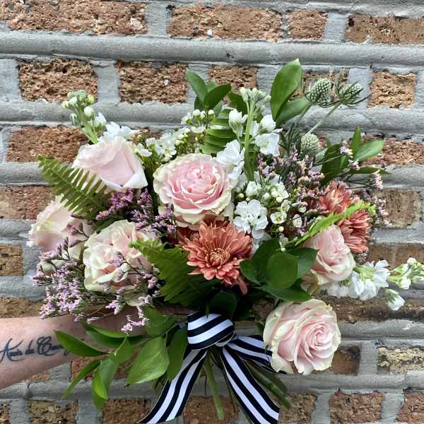 Hand-tied bouquet of pale pink roses, peach mums, and white blooms with a striped ribbon