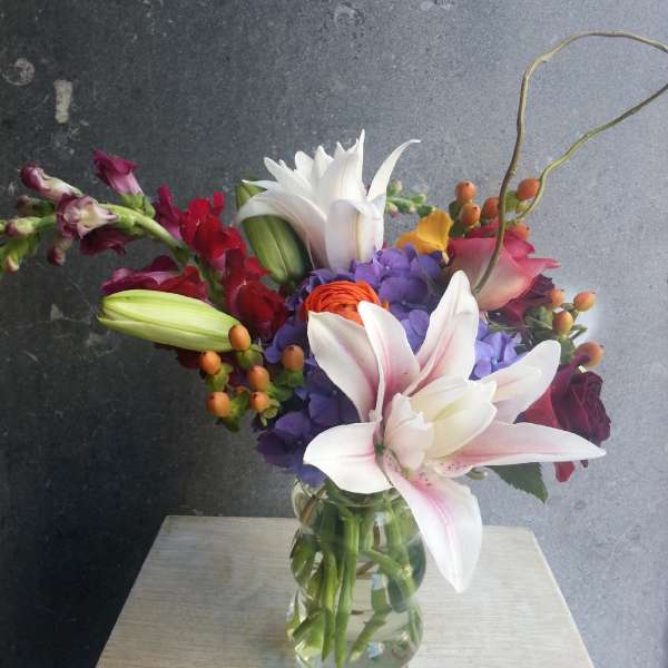 Mixed bouquet with lilies, hydrangeas, roses, and snapdragons in a glass vase