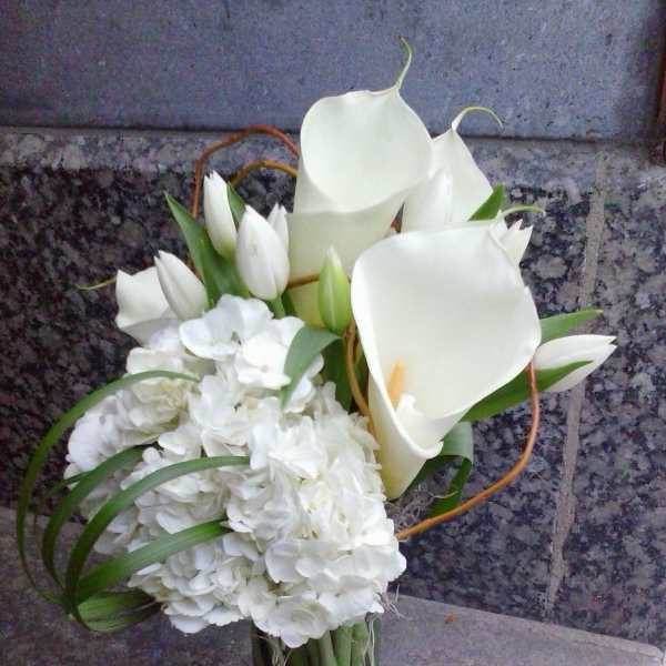 White calla lilies and hydrangeas in a glass vase