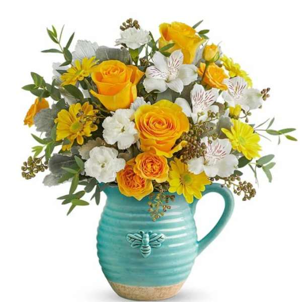 Yellow and white flower bouquet in a turquoise pitcher vase