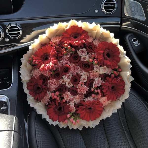 Bouquet of red gerbera daisies and roses wrapped in cream paper
