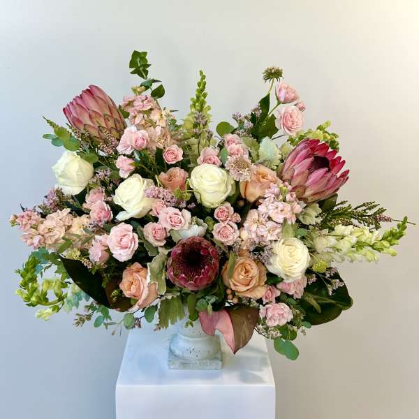 Large pastel bouquet with roses and protea in a white vase