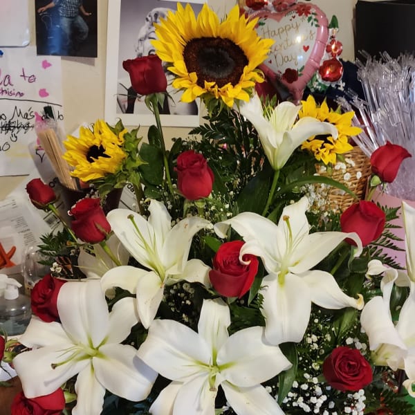 Basket arrangement with white lilies, red roses, and sunflowers