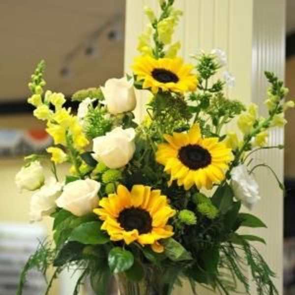 Sunflowers and white roses arranged in a clear glass vase