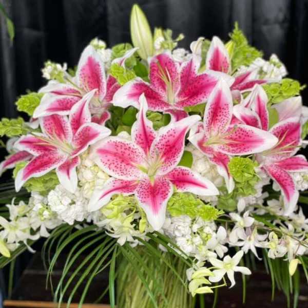 Pink stargazer lilies and white flowers in a glass vase