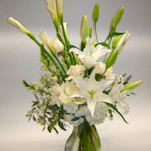 White lilies and calla lilies in a clear glass vase