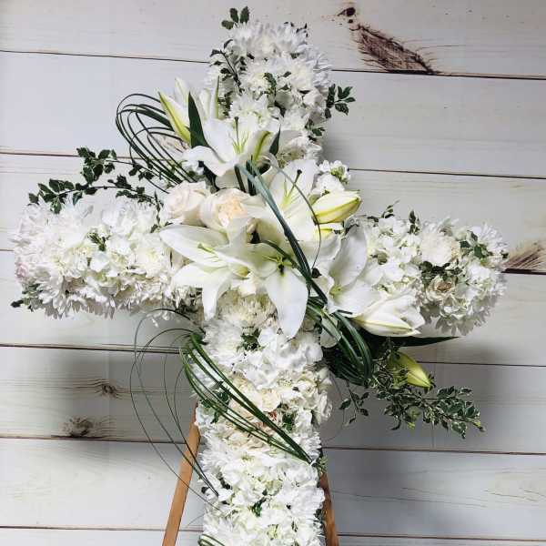 White floral cross arrangement on a wooden easel