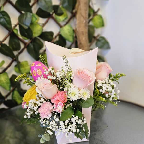 Small bouquet of pink roses, white daisies, and baby’s breath in a paper sleeve