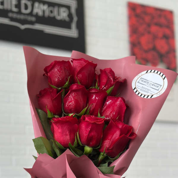 Bouquet of red roses wrapped in pink paper with a black ribbon