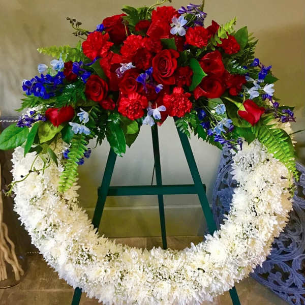 Large floral wreath with red roses and white flowers on a stand