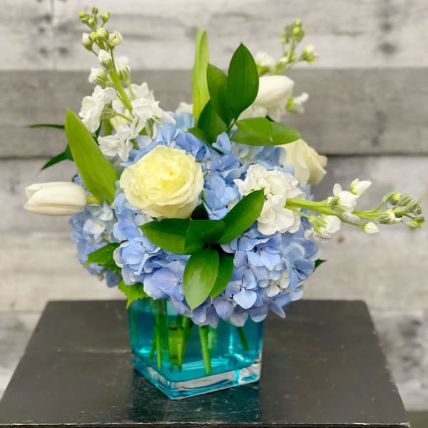 Blue hydrangea bouquet with white roses in a blue glass vase