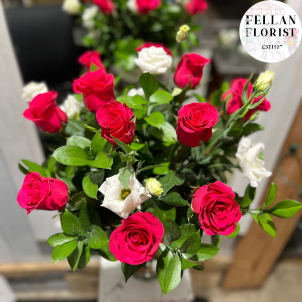 Arrangement of bright pink roses and white lisianthus in a clear glass vase