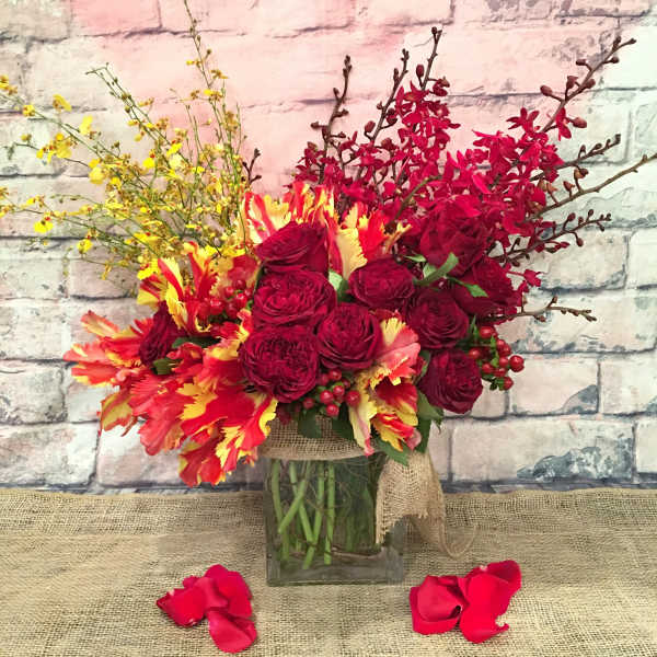 Bouquet of red roses and yellow-red flowers in a glass vase