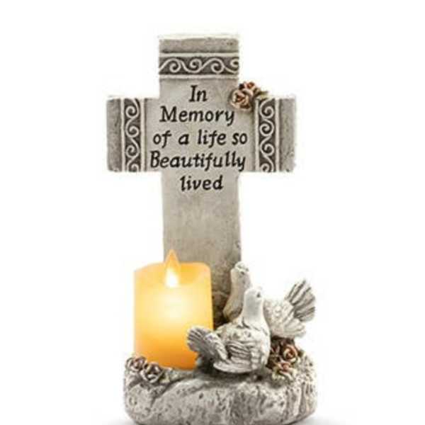 Memorial cross with a lit candle and dove figurines