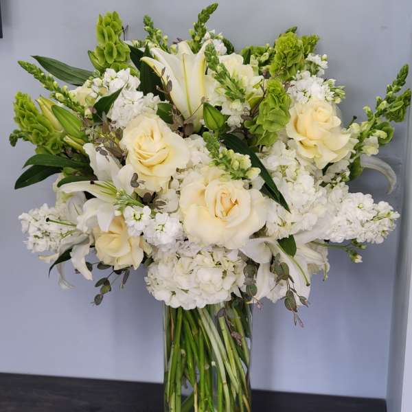 Cream roses and white lilies in a tall glass vase