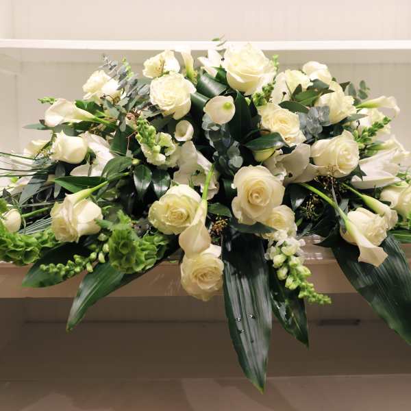 Low spray of white roses and calla lilies arranged in an elongated shape