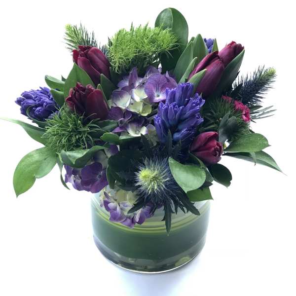 Purple and burgundy floral arrangement in a glass vase