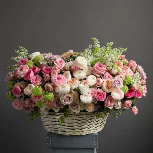 Large basket of pink and peach roses and ranunculus with soft white and green accents