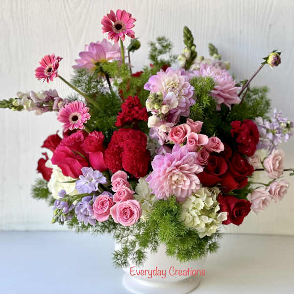 Mixed pink and red flower arrangement in a white vase