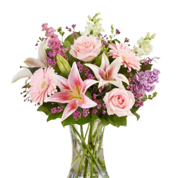 Pink roses and lilies arranged in a clear glass vase