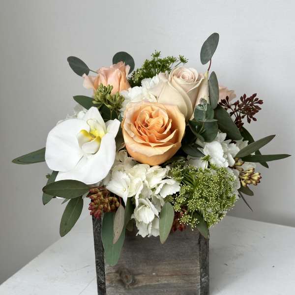 Peach and white roses with a white orchid in a wooden box