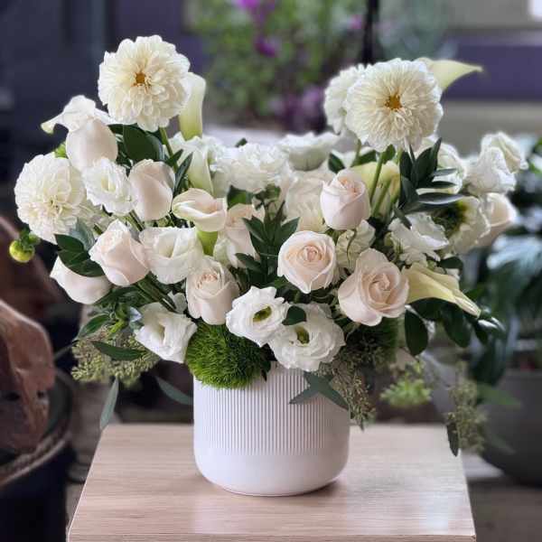 White floral arrangement in a ribbed white vase