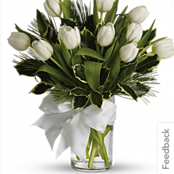 White tulip bouquet in a clear glass vase with a white ribbon