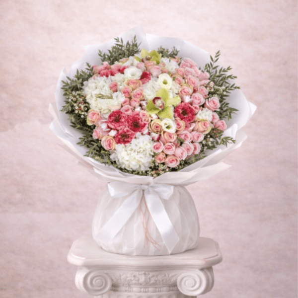 Large round bouquet of pink spray roses and white hydrangeas wrapped in white paper and ribbon
