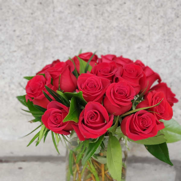 Arrangement of red roses tightly clustered in a clear glass vase