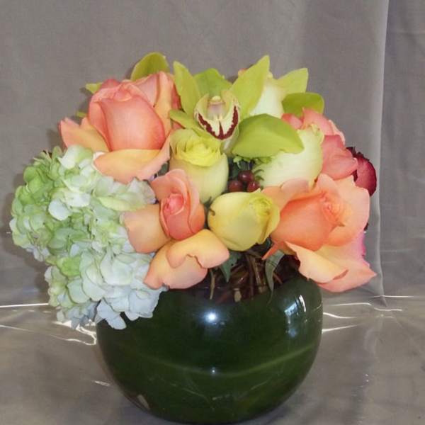 Bouquet of peach roses and pale hydrangea in a dark green vase