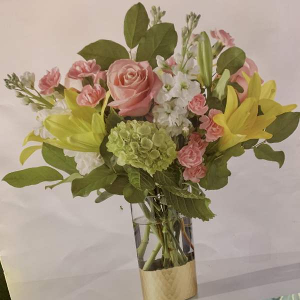 Pink roses and lilies arranged in a clear glass vase