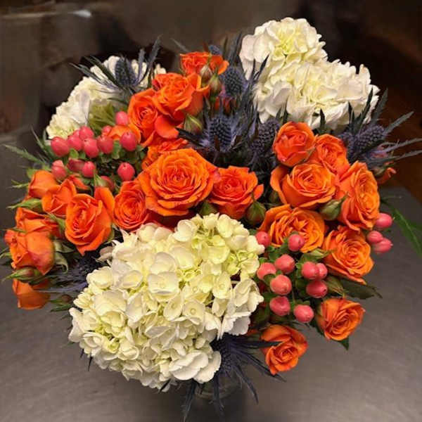 Bouquet of orange roses and white hydrangeas with pink berries