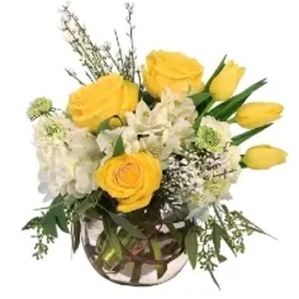 Yellow roses and white flowers arranged in a glass vase