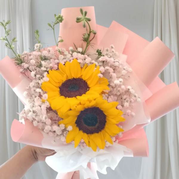 Bouquet of two sunflowers with pink baby's breath in pastel wrapping