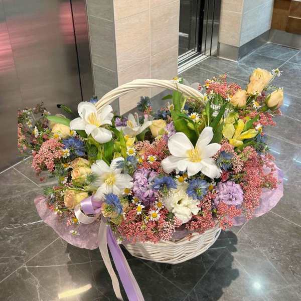 Large basket arrangement of mixed pastel flowers with white blooms and pink accents