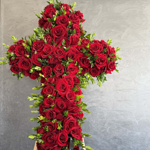 Large cross-shaped arrangement of red roses on a stand