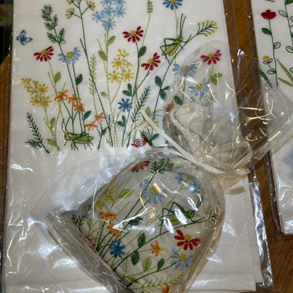 Embroidered floral napkins and a matching heart-shaped pouch in plastic wrap
