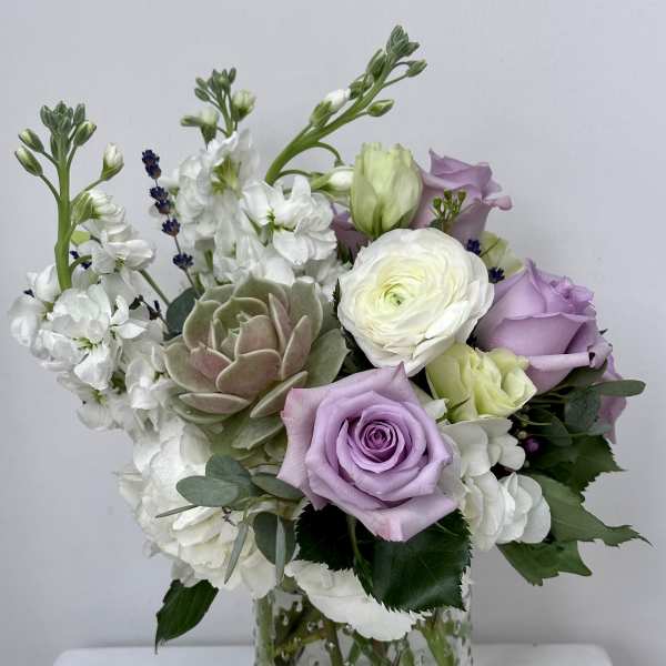 Lavender and white roses with ranunculus in a clear glass vase