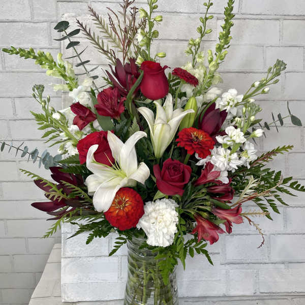 Red and white mixed flower arrangement in a glass vase