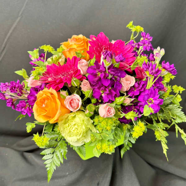 Bright mixed bouquet with orange roses, pink blooms, and purple flowers